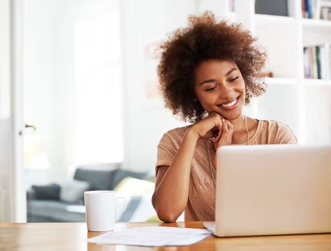 mulher sentada em uma mesa mexendo no notebook aproveitando o plano de internet da claro